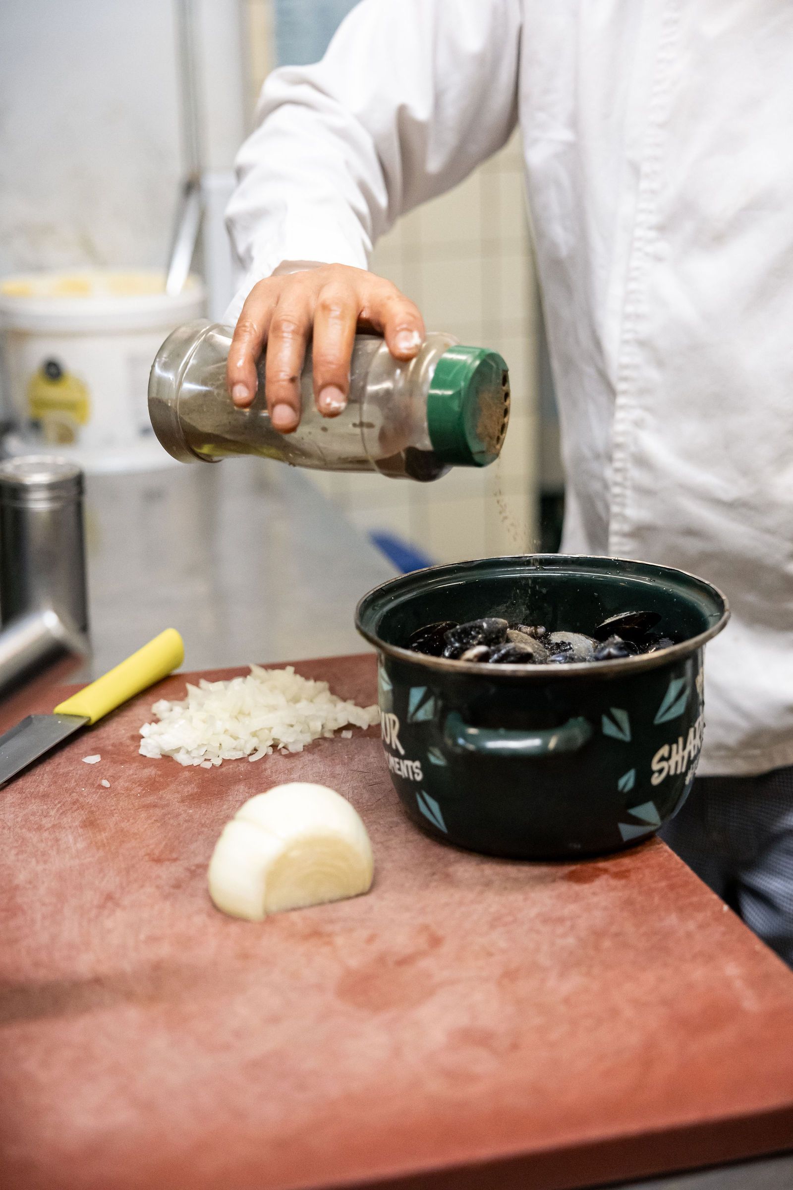 Casserole de moules fraîches et oignons émincés sur le plan de travail de la cuisine
