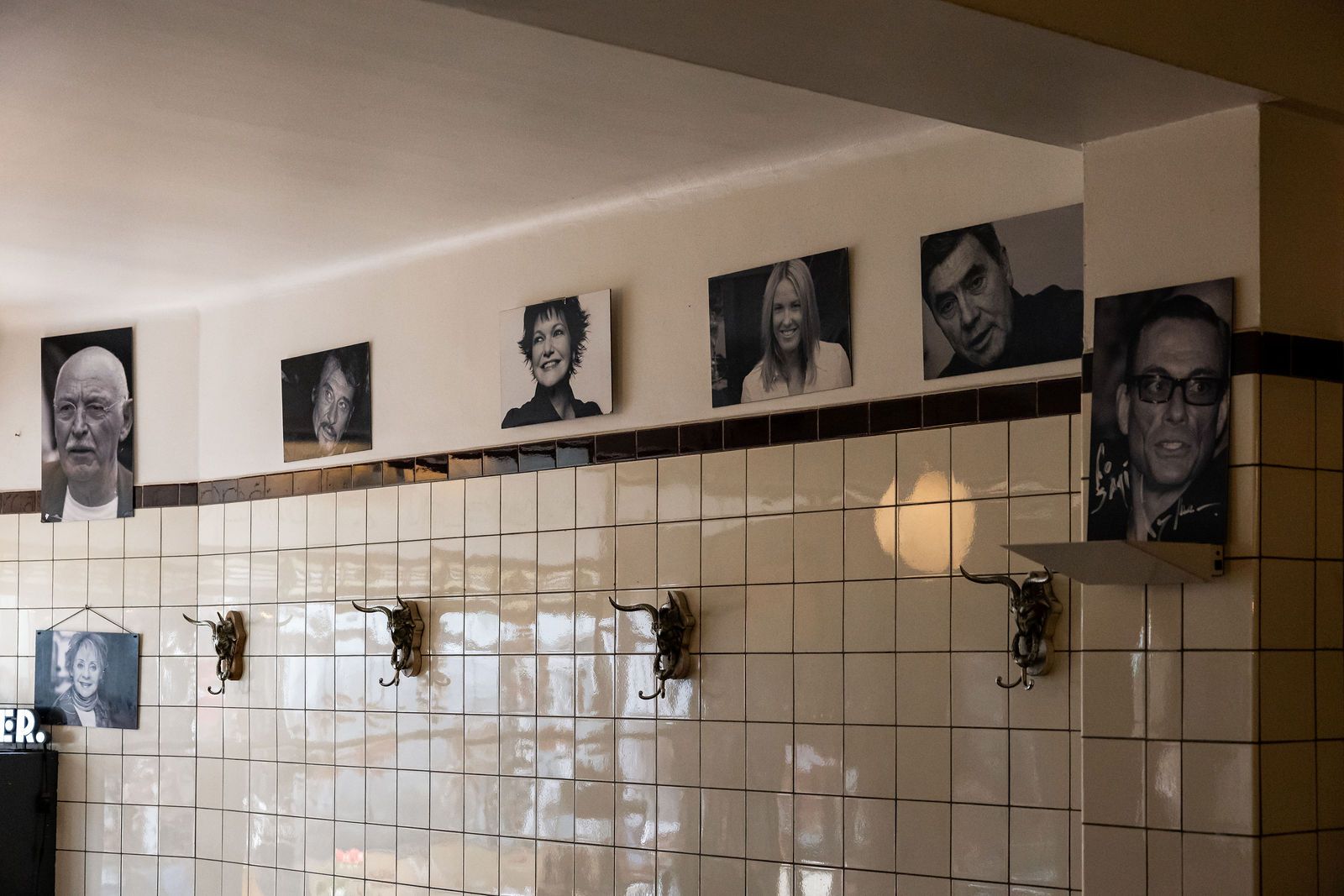 Mur de portraits en noir et blanc sur le carrelage blanc de la salle