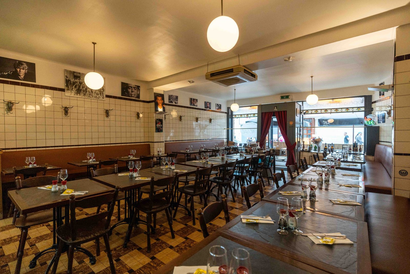 Salle du Pré Salé vue vers la rue : faïence blanche, portraits en noir et blanc et longues tables de brasserie